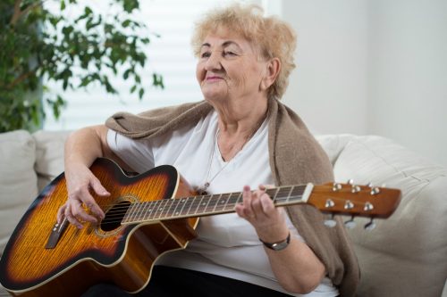 Oudere dame speelt op een gitaar
