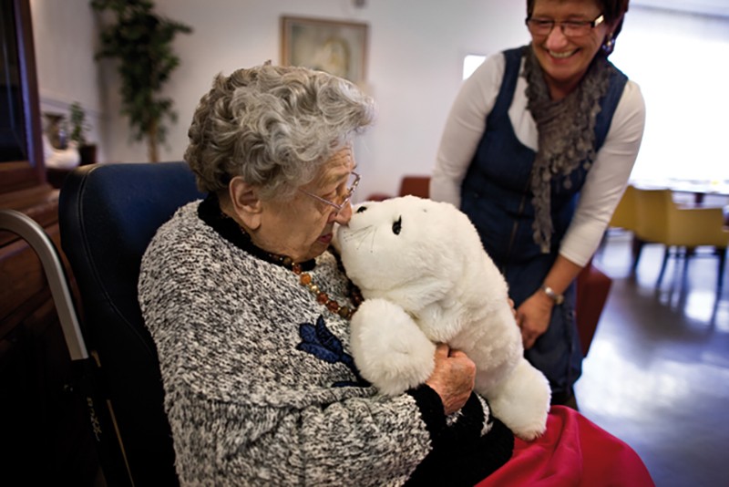 Dementerende vrouw knuffelt Paro, de knuffelrobot Dementerende vrouw knuffelt Paro, de knuffelrobot