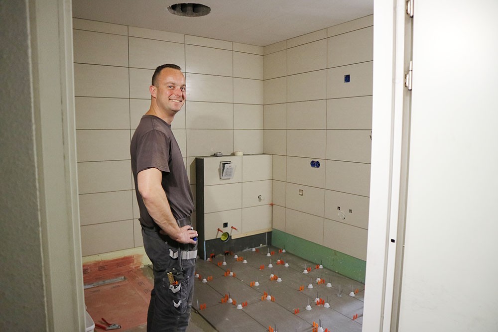 Jasper de Heij is bezig met de betegeling van de badkamervloer Jasper de Heij is bezig met de betegeling van de badkamervloer