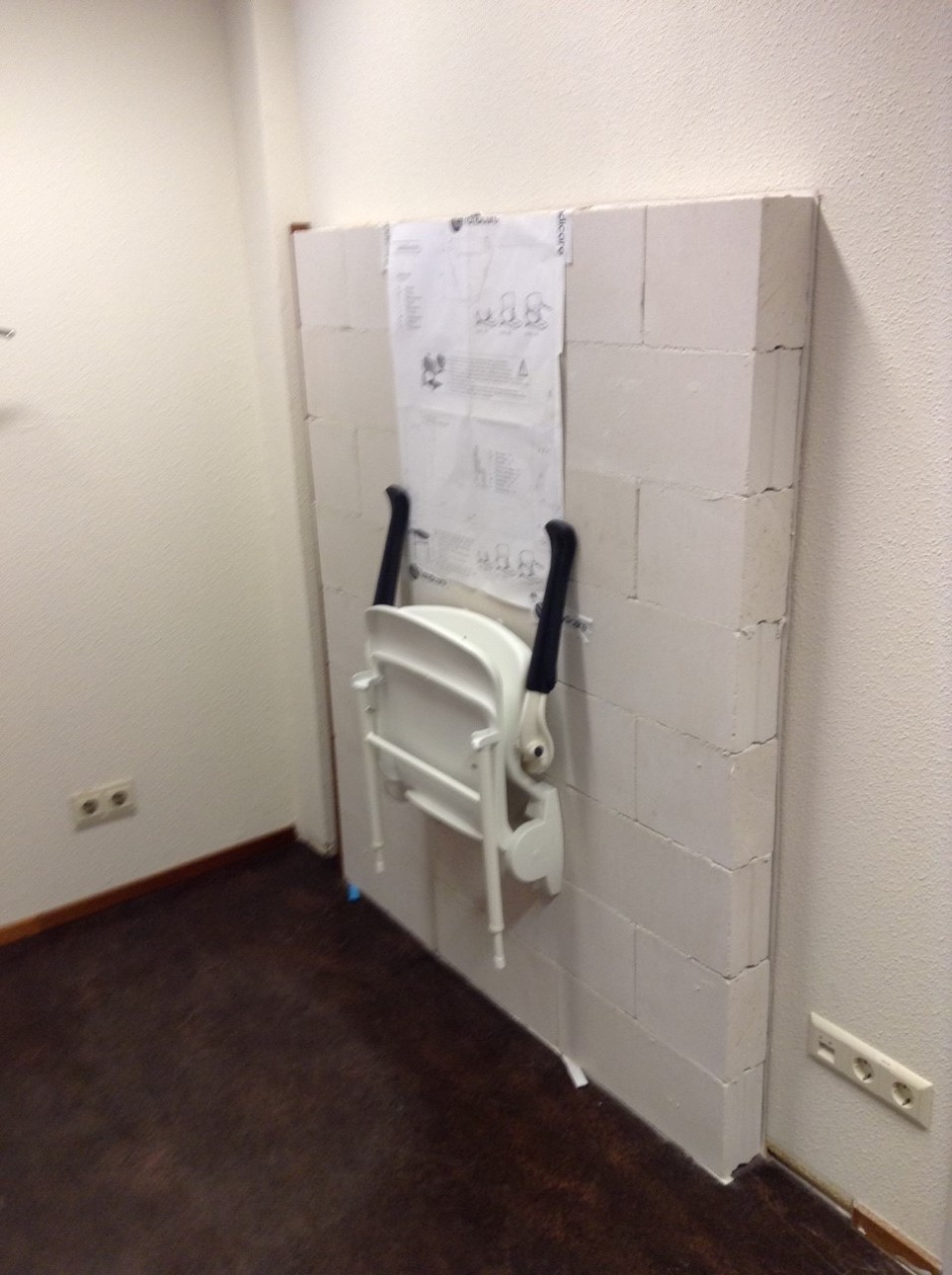 Oefenmuur voor het plaatsen van douchezitjes met opklapbare poten, met de Handicare-montageposter | Handicare Academy Oefenmuur voor het plaatsen van douchezitjes met opklapbare poten, met de Handicare-montageposter | Handicare Academy