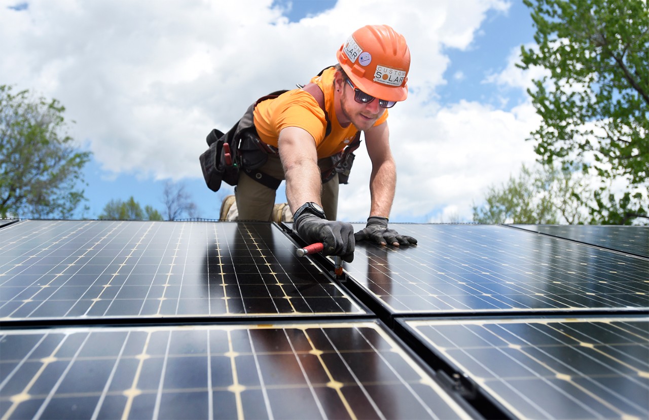 Installateur plaatst zonnepanelen op een rietdak Installateur plaatst zonnepanelen op een rietdak